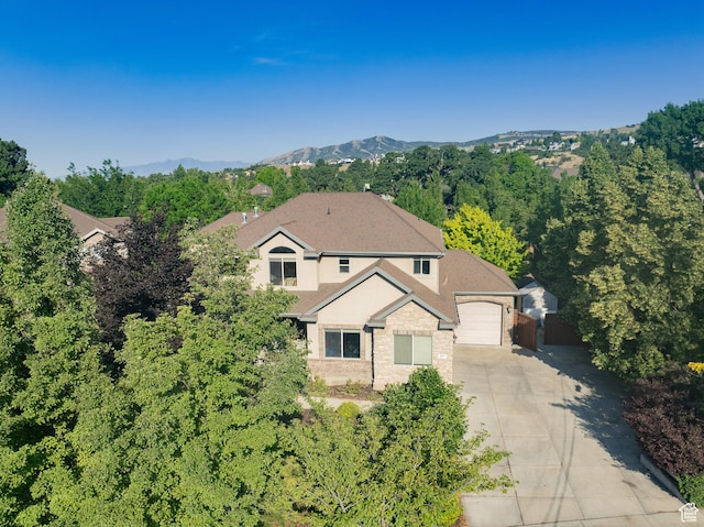 357 N Main St, Alpine, UT 84004 - view of front of home with driveway, an attached garage, stone siding, stucco siding, and a mountain view