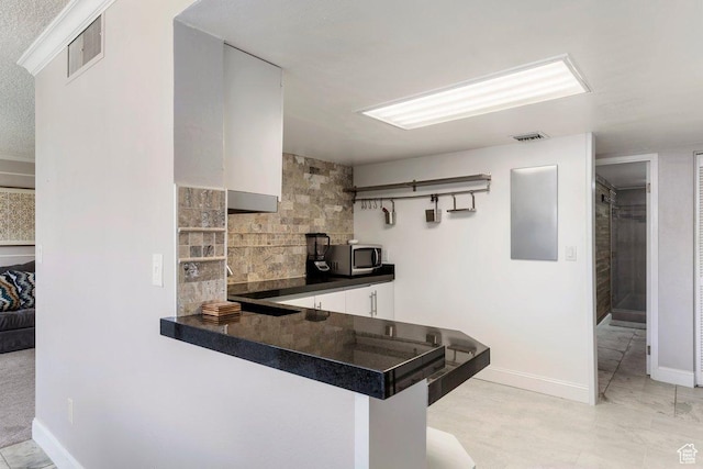 241 N Vine St Unit 506W, Salt Lake City, UT 84103 - kitchen featuring dark countertops, stainless steel microwave, tasteful backsplash, white cabinetry, and a peninsula