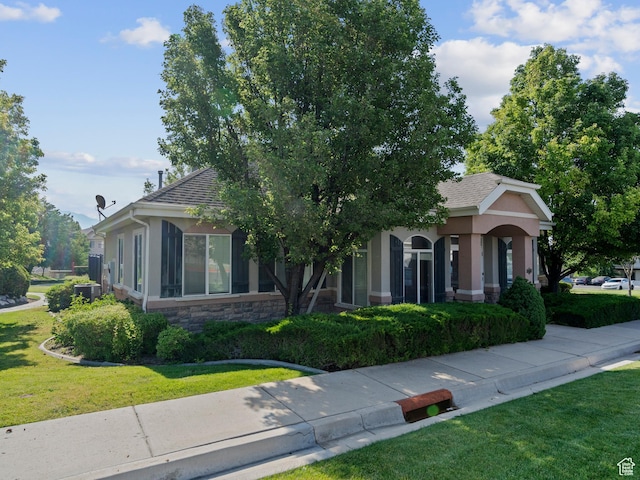 2119 N Aurora Way Unit F, Saratoga Springs, UT 84045 - view of property hidden behind natural elements featuring a front lawn, stucco siding, roof with shingles, and stone siding
