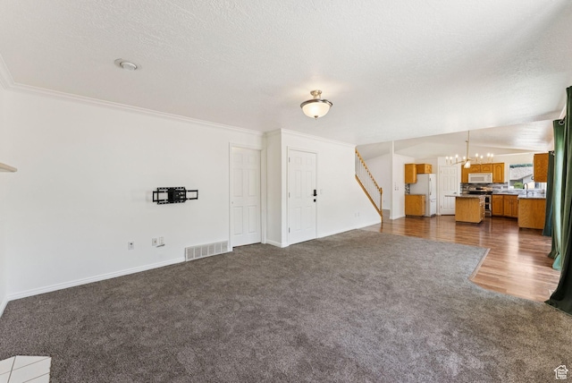2198 N 1600 E, Layton, UT 84040 - unfurnished living room with a chandelier, dark colored carpet, stairway, crown molding, and a textured ceiling