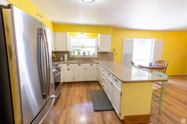 1471 W Stern Dr S, Taylorsville, UT 84123 - kitchen with appliances with stainless steel finishes, a peninsula, a breakfast bar area, and backsplash