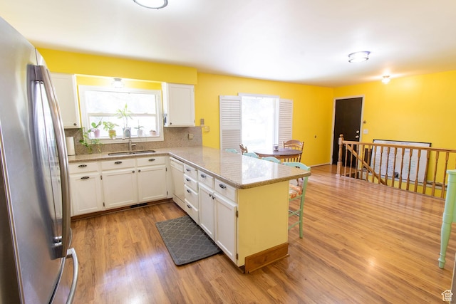 1471 W Stern Dr S, Taylorsville, UT 84123 - kitchen featuring freestanding refrigerator, tasteful backsplash, light wood finished floors, a peninsula, and white cabinetry
