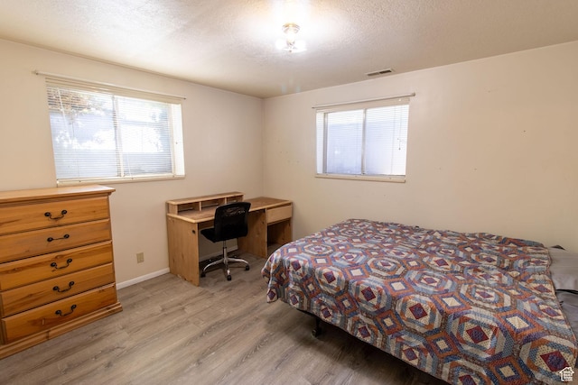 1471 W Stern Dr S, Taylorsville, UT 84123 - bedroom with light wood finished floors, multiple windows, and a textured ceiling