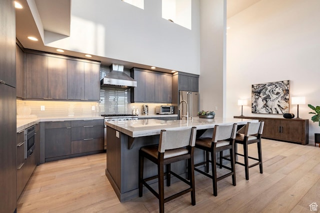 6836 Golden Bear Loop W, Park City, UT 84098 - kitchen with wall chimney exhaust hood, a high ceiling, stainless steel appliances, a kitchen breakfast bar, and modern cabinets