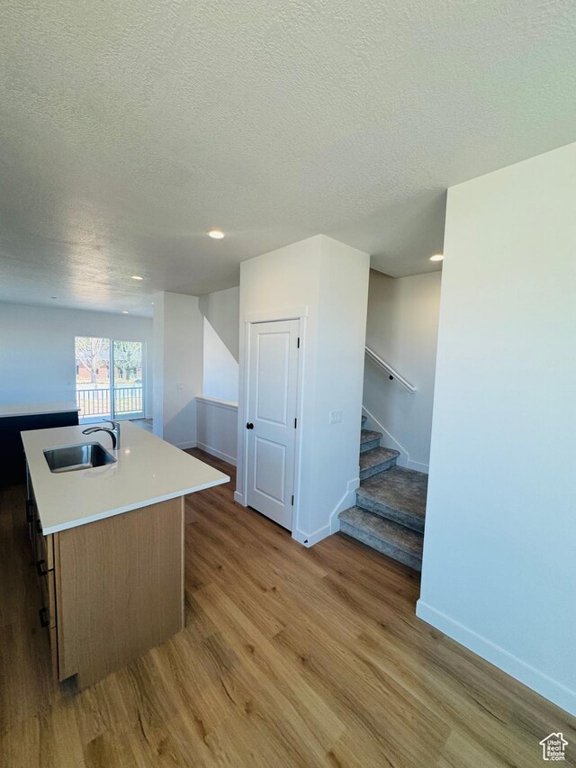 1650 N Main St Unit 126, Layton, UT 84041 - kitchen with light wood-type flooring, a textured ceiling, light countertops, a kitchen island with sink, and recessed lighting