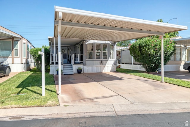 2990 E Riverside Dr Unit 3, St George, UT 84790 - view of front of property with an attached carport, a front yard, a sunroom, entry steps, and driveway