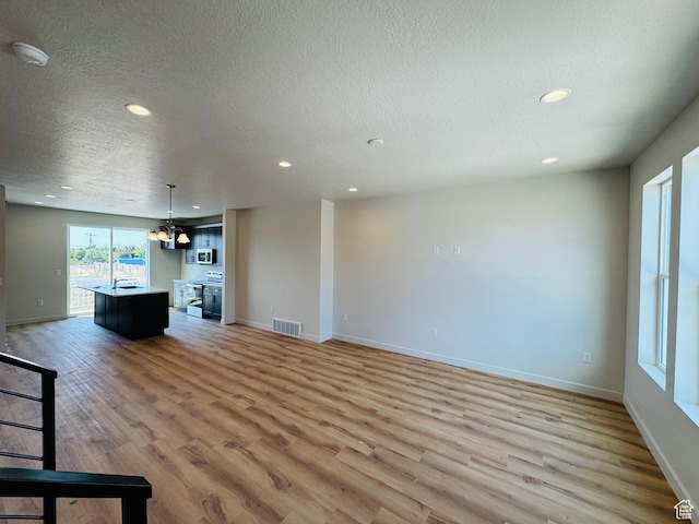 1682 N 1600 W Unit 124, Layton, UT 84041 - unfurnished living room with light wood finished floors, a textured ceiling, and recessed lighting