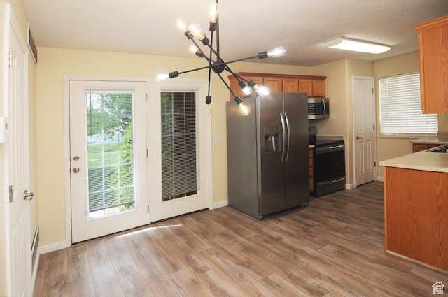 1511 W Leonardo Ln Unit D, West Valley City, UT 84119 - kitchen with appliances with stainless steel finishes, a chandelier, brown cabinetry, wood finished floors, and light countertops