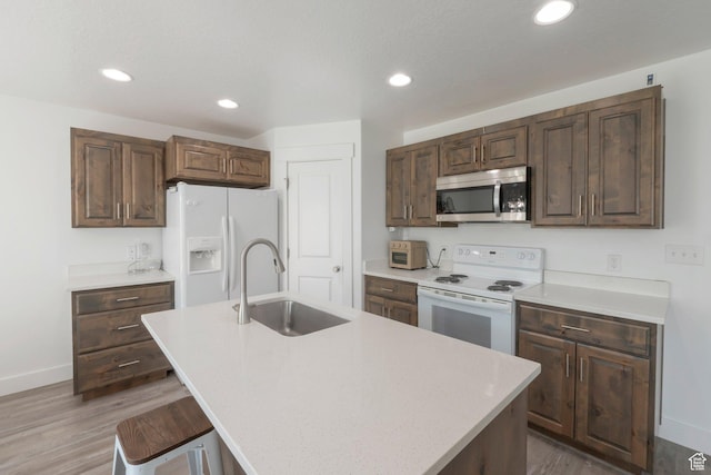 721 S 110 W, Spanish Fork, UT 84660 - kitchen with white appliances, light countertops, light wood finished floors, a kitchen island with sink, and recessed lighting