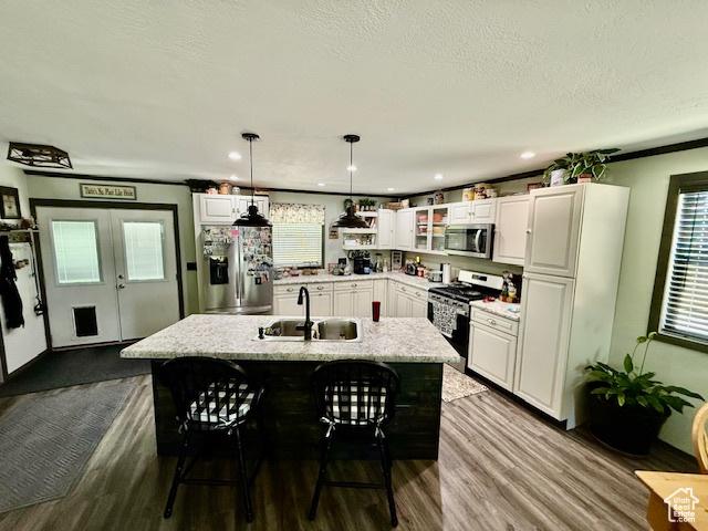 536 N Sundance Cir, Vernal, UT 84078 - kitchen with stainless steel appliances, dark wood finished floors, white cabinets, a breakfast bar, and hanging light fixtures