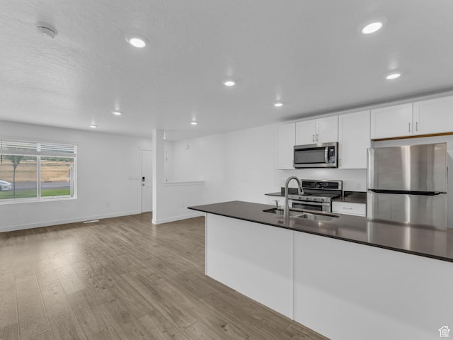 1206 W Summit Ridge Pkwy S Unit 182, Santaquin, UT 84655 - kitchen with appliances with stainless steel finishes, dark countertops, light wood finished floors, white cabinetry, and recessed lighting