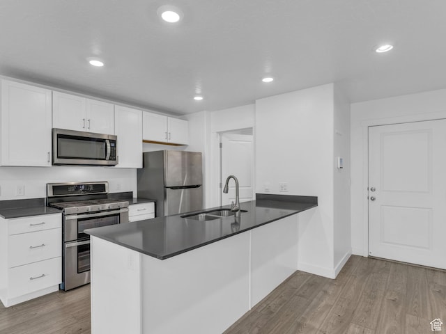 1206 W Summit Ridge Pkwy S Unit 182, Santaquin, UT 84655 - kitchen with stainless steel appliances, dark countertops, wood finished floors, white cabinetry, and a peninsula