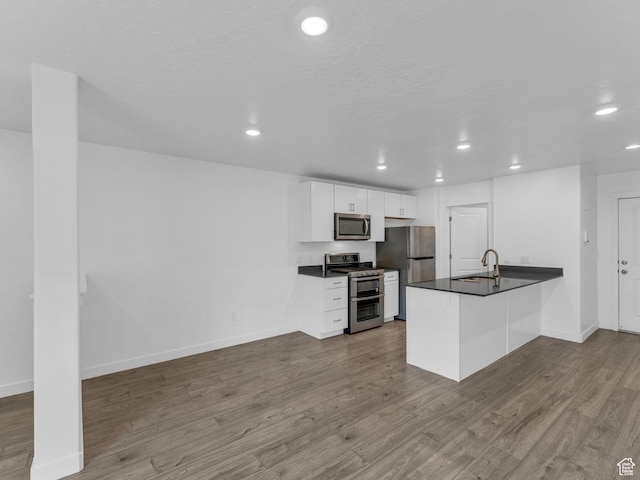 1206 W Summit Ridge Pkwy S Unit 182, Santaquin, UT 84655 - kitchen with appliances with stainless steel finishes, dark countertops, a peninsula, recessed lighting, and dark wood finished floors