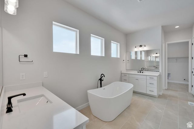 273 E Polaris Dr Unit 103, Saratoga Springs, UT 84045 - bathroom with two vanities, a freestanding tub, a walk in closet, and recessed lighting
