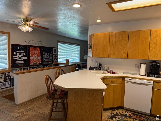 2936 E Ln Joya Dr S, Holladay, UT 84124 - kitchen with white dishwasher, a peninsula, a kitchen breakfast bar, ceiling fan, and light countertops