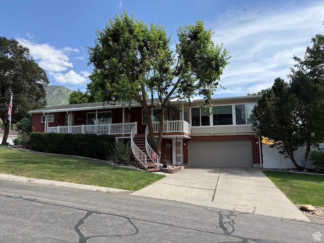 2936 E Ln Joya Dr S, Holladay, UT 84124 - view of front of property featuring brick siding, an attached garage, concrete driveway, a front lawn, and covered porch