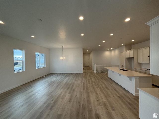 284 E Polaris Dr Unit 112, Saratoga Springs, UT 84045 - kitchen featuring recessed lighting, light wood-type flooring, light countertops, a center island with sink, and a chandelier