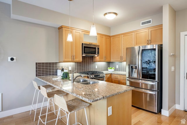 1988 S 1100 E Unit 308, Salt Lake City, UT 84105 - kitchen featuring stainless steel appliances, a peninsula, light stone countertops, tasteful backsplash, and light wood-style floors