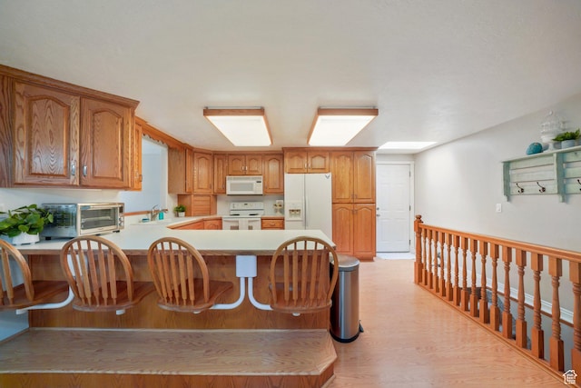 117 E 300 S, Gunnison, UT 84634 - kitchen featuring white appliances, light countertops, a peninsula, a kitchen breakfast bar, and brown cabinets