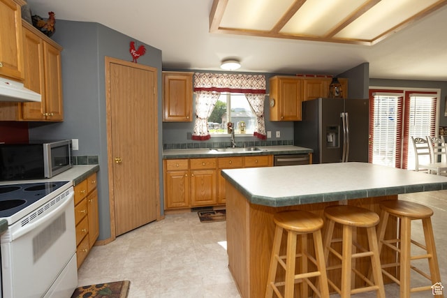 205 W 575 S, Venice, UT 84701 - kitchen with stainless steel appliances, a kitchen breakfast bar, under cabinet range hood, a center island, and brown cabinetry