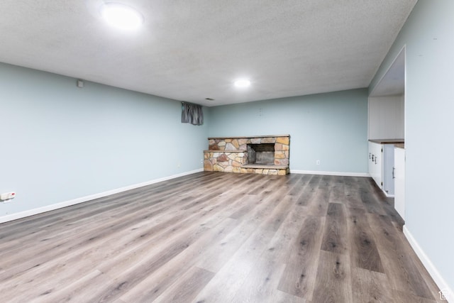 5681 S Calann Dr E, Holladay, UT 84121 - unfurnished living room with a stone fireplace, wood finished floors, and a textured ceiling