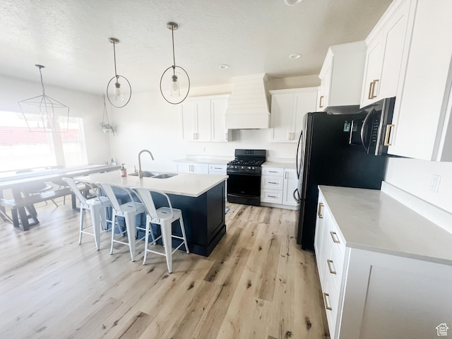 291 W 950 S, Vernal, UT 84078 - kitchen with custom range hood, black appliances, a chandelier, light wood-type flooring, and light countertops
