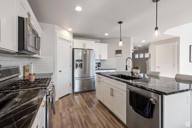12333 S Pesky Ln, Herriman, UT 84096 - kitchen with appliances with stainless steel finishes, dark wood-type flooring, an island with sink, white cabinetry, and decorative light fixtures