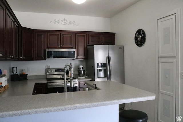 1521 N 420 W Unit 104, Logan, UT 84341 - kitchen with stainless steel appliances, light countertops, dark brown cabinetry, a peninsula, and a kitchen bar