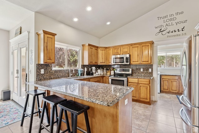562 E 260 S, Midway, UT 84049 - kitchen featuring stainless steel appliances, light stone countertops, lofted ceiling, light tile patterned flooring, and a breakfast bar area