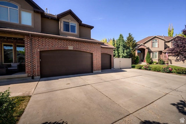 3371 W Waterbridge Cv Unit 417, South Jordan, UT 84095 - view of front of house featuring driveway, an attached garage, brick siding, and stucco siding