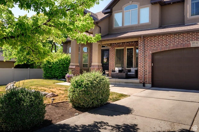 3371 W Waterbridge Cv Unit 417, South Jordan, UT 84095 - view of exterior entry with a garage, stucco siding, driveway, brick siding, and covered porch