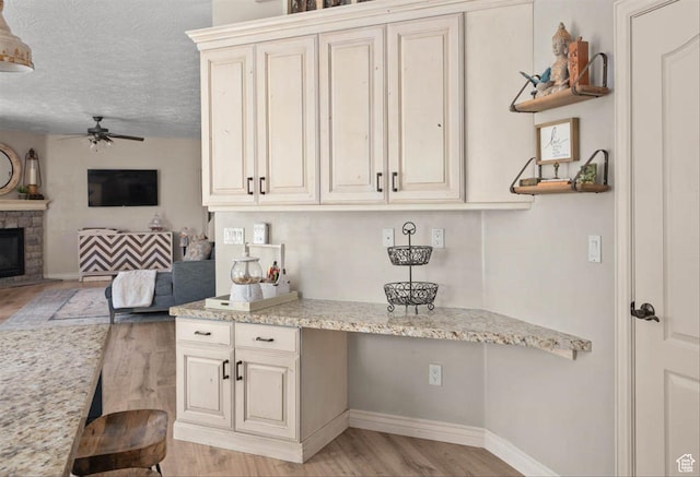 3371 W Waterbridge Cv Unit 417, South Jordan, UT 84095 - kitchen featuring light wood finished floors, ceiling fan, a textured ceiling, open floor plan, and light stone counters