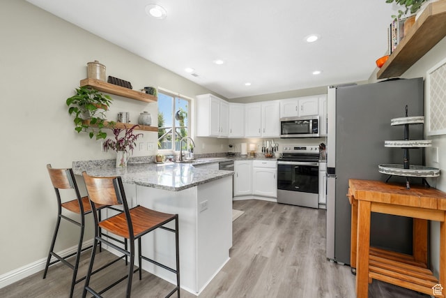 948 N 140 W, American Fork, UT 84003 - kitchen with appliances with stainless steel finishes, a peninsula, white cabinetry, light wood-type flooring, and light stone counters