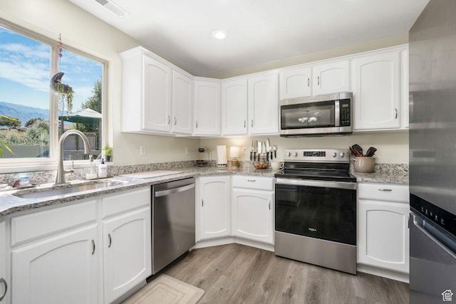 948 N 140 W, American Fork, UT 84003 - kitchen with appliances with stainless steel finishes, white cabinets, light wood-type flooring, light stone countertops, and recessed lighting