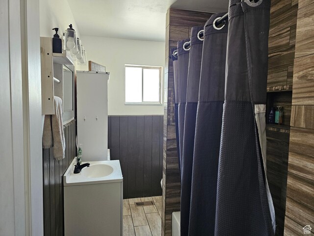 92 W 300 N, Huntington, UT 84528 - bathroom featuring vanity, shower / bathtub combination with curtain, a wainscoted wall, wood finished floors, and wood walls