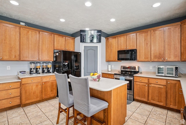 13626 S Bluewing Way, Riverton, UT 84096 - kitchen with black appliances, a breakfast bar area, brown cabinets, light countertops, and recessed lighting