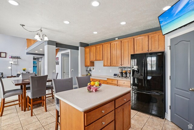 13626 S Bluewing Way, Riverton, UT 84096 - kitchen with black refrigerator with ice dispenser, a center island, light countertops, recessed lighting, and brown cabinets