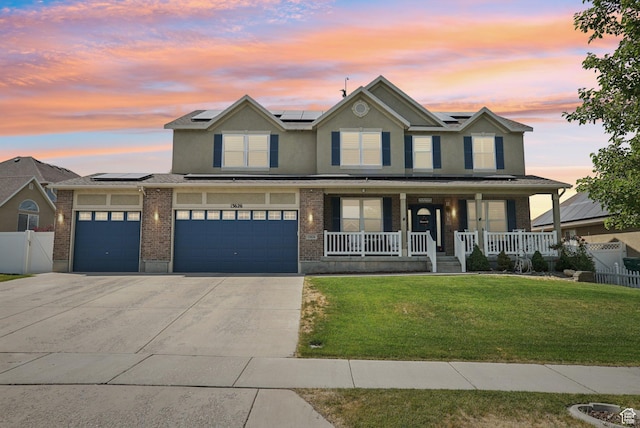 13626 S Bluewing Way, Riverton, UT 84096 - view of front of house with a porch, roof mounted solar panels, concrete driveway, brick siding, and stucco siding
