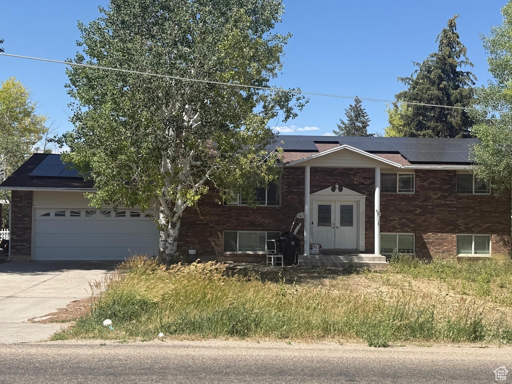 3438 W 500 S, Vernal, UT 84078 - bi-level home with roof mounted solar panels, concrete driveway, brick siding, and an attached garage