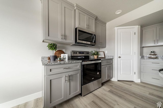 2259 S 1180 W Unit 12, Nibley, UT 84321 - kitchen featuring stainless steel appliances, gray cabinets, light stone counters, light wood-style floors, and a textured ceiling