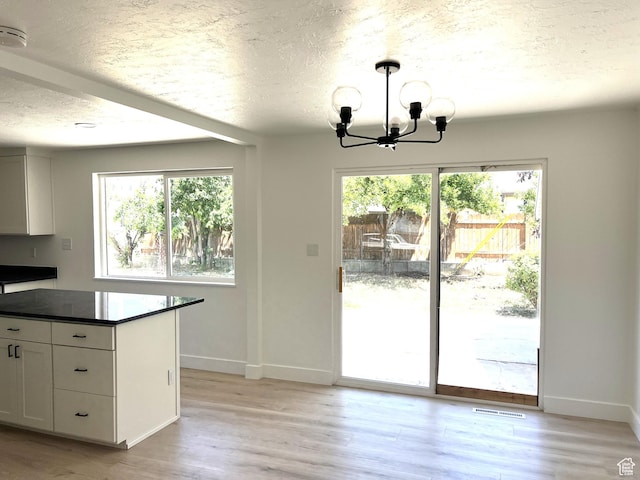 686 N Parkway Ave, Tooele, UT 84074 - kitchen featuring dark countertops, healthy amount of natural light, a chandelier, light wood-type flooring, and a textured ceiling