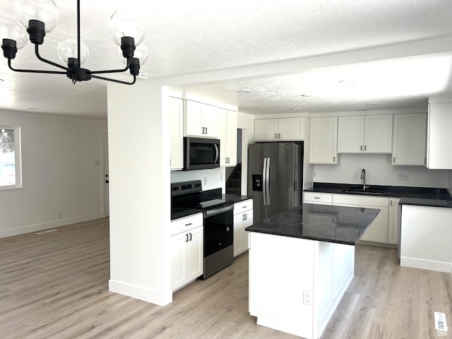 686 N Parkway Ave, Tooele, UT 84074 - kitchen featuring appliances with stainless steel finishes, a chandelier, light wood-style flooring, a textured ceiling, and a center island