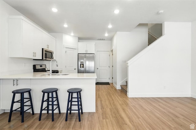 1221 W 1870 S, Logan, UT 84321 - kitchen with stainless steel appliances, light wood finished floors, a peninsula, a kitchen breakfast bar, and recessed lighting