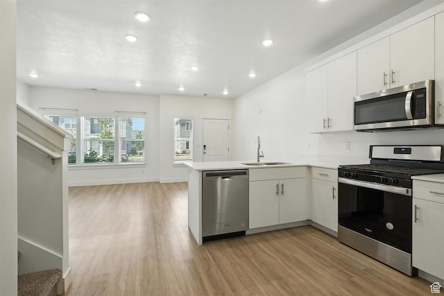 1221 W 1870 S, Logan, UT 84321 - kitchen featuring appliances with stainless steel finishes, light wood-style flooring, a peninsula, recessed lighting, and white cabinetry