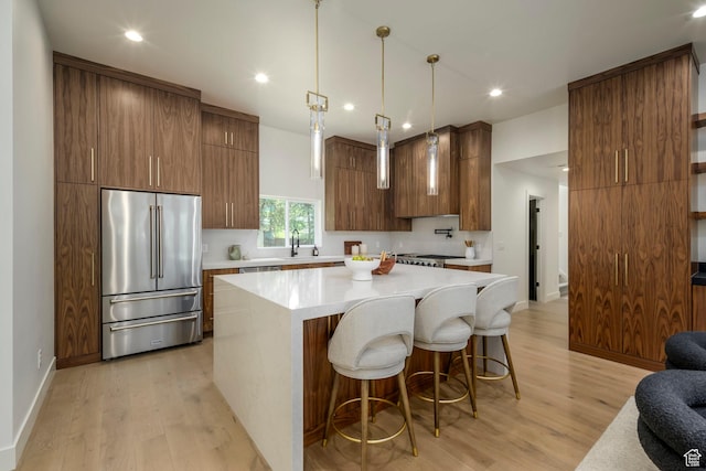 1958 E Longview Dr, Holladay, UT 84124 - kitchen featuring high end fridge, light wood-style floors, light countertops, a breakfast bar area, and a center island