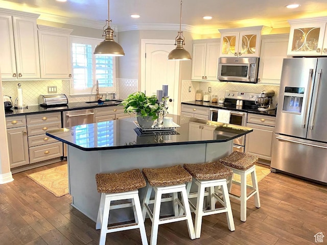 4854 N Shady Bend Ln, Lehi, UT 84043 - kitchen featuring appliances with stainless steel finishes, dark countertops, a kitchen bar, a center island, and tasteful backsplash