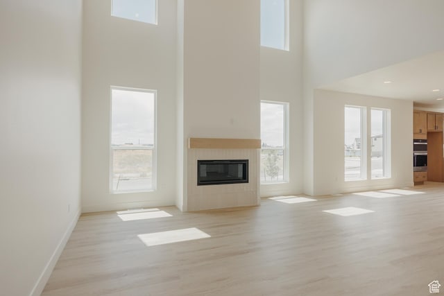 1026 W Chokecherry Dr Unit 135, Mapleton, UT 84664 - unfurnished living room with a towering ceiling, a fireplace, and light wood-type flooring