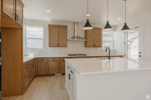 1026 W Chokecherry Dr Unit 135, Mapleton, UT 84664 - kitchen featuring wall chimney exhaust hood, gas cooktop, a center island with sink, light wood-style floors, and brown cabinets