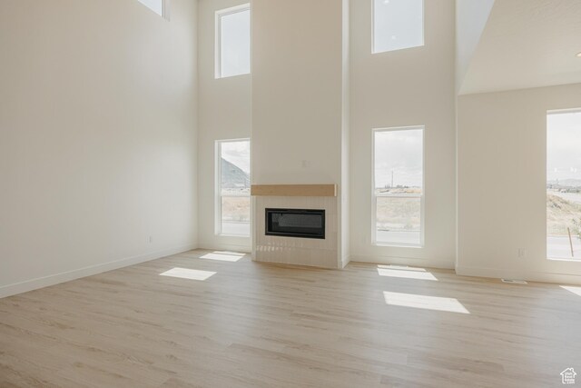 1026 W Chokecherry Dr Unit 135, Mapleton, UT 84664 - unfurnished living room with a towering ceiling, light wood-style floors, and a tile fireplace