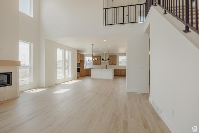 1026 W Chokecherry Dr Unit 135, Mapleton, UT 84664 - unfurnished living room featuring a high ceiling, light wood-type flooring, healthy amount of natural light, a tiled fireplace, and recessed lighting